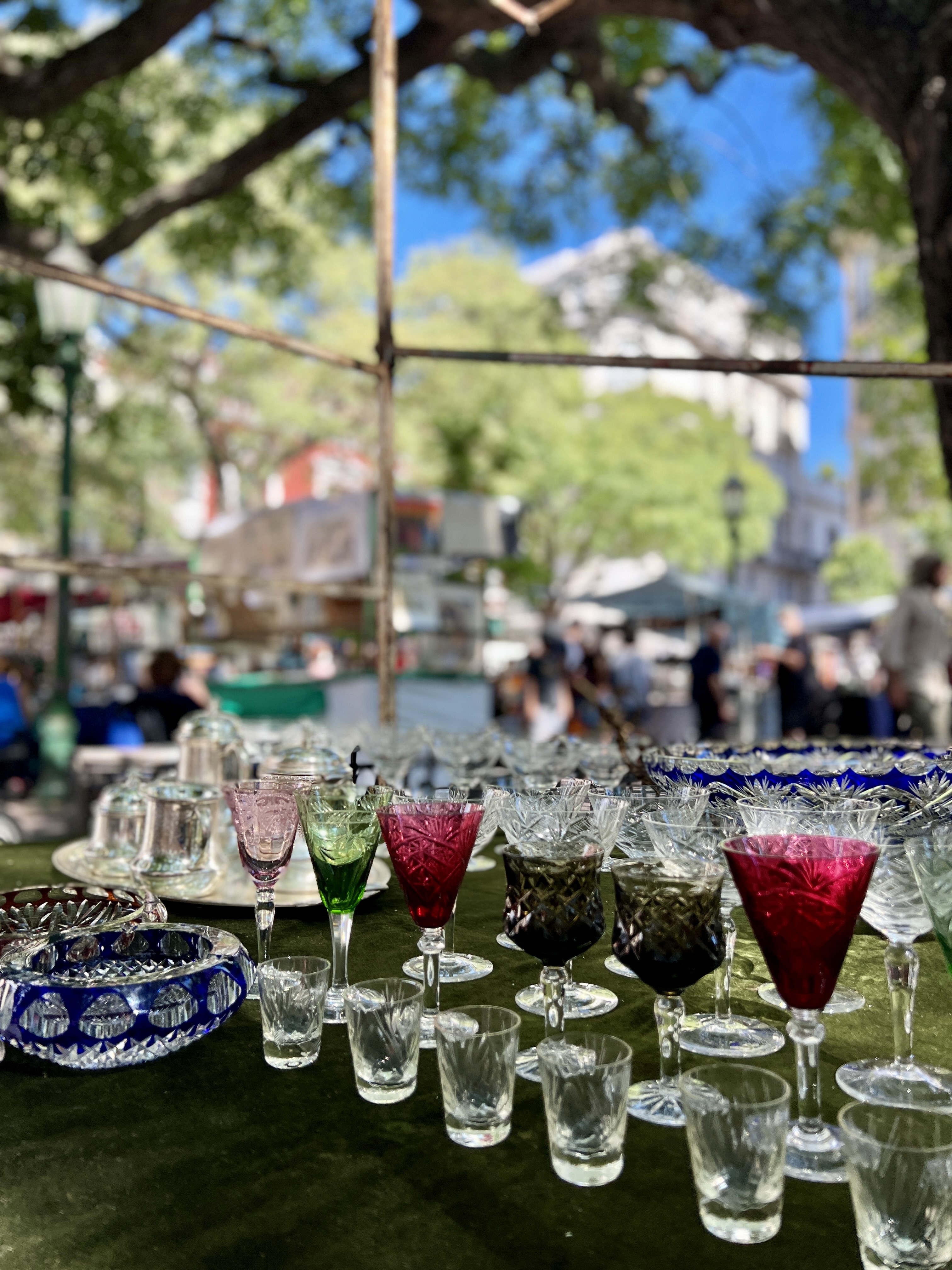 Several antique glasses are displayed on a table at the San Telmo Market in Buenos Aires