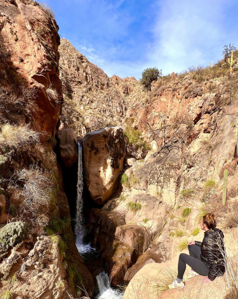 camino de los siete cascadas is a hiking trail outside of cafayate argentina. I am sitting in front of one of the large waterfalls along the hike.