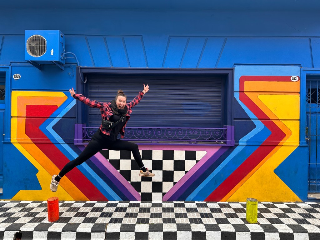 Nicki jumping in front of a colorful mural in Palermo Soho