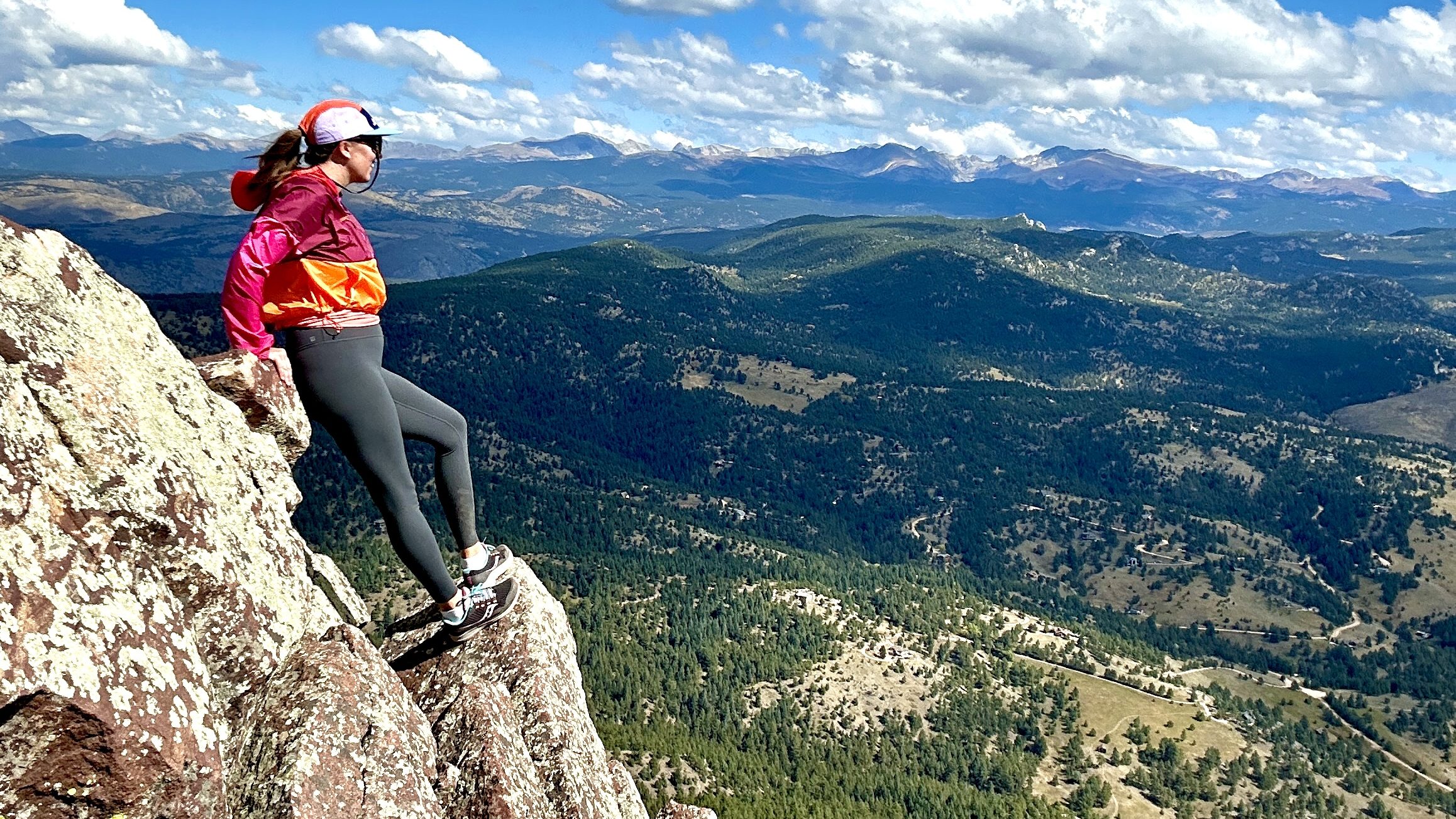 Nicki stands on top of a rock at the summit of South Boulder Peak