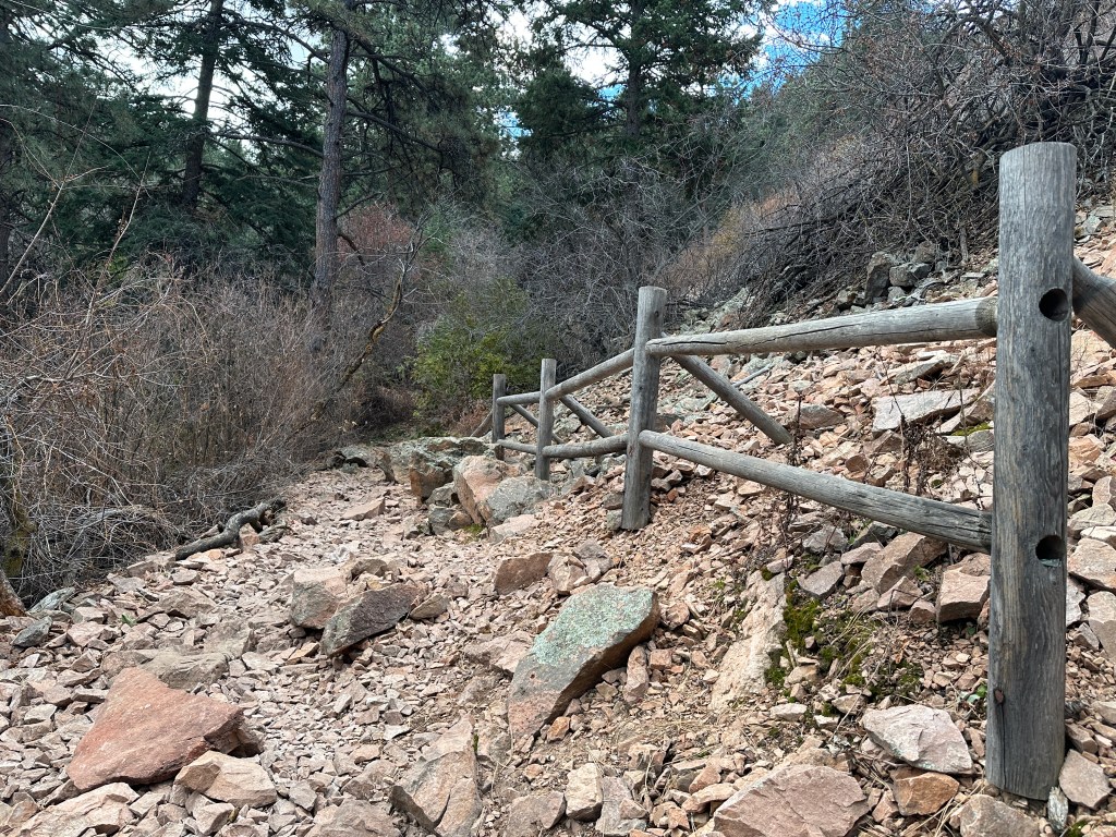 The rocky path along the start of the Amphitheater Trail. There is a wooden fence on the right side.