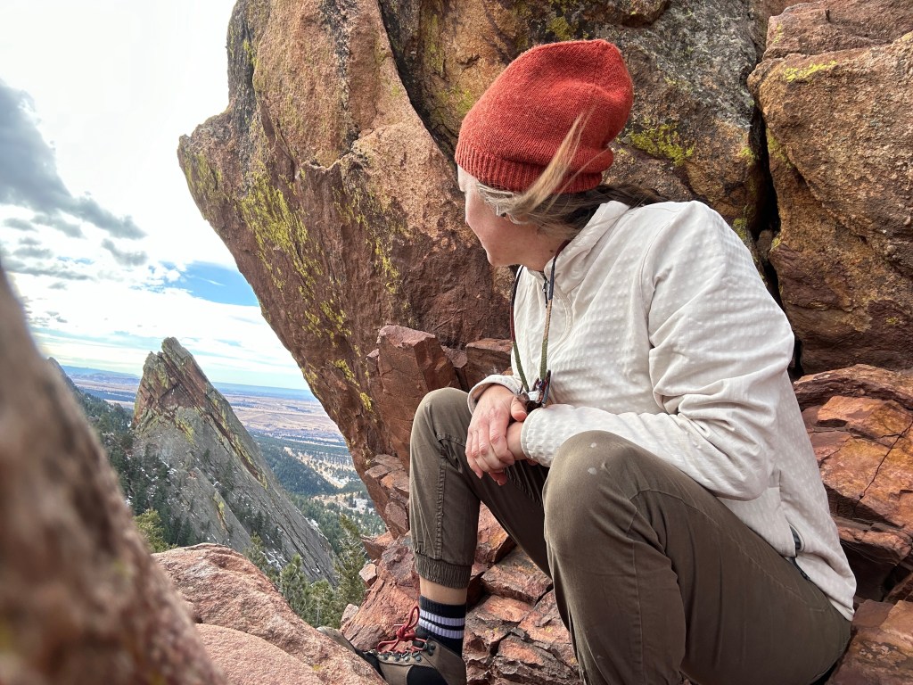 Nicki sits on top of the flatirons looking out over the other peaks.