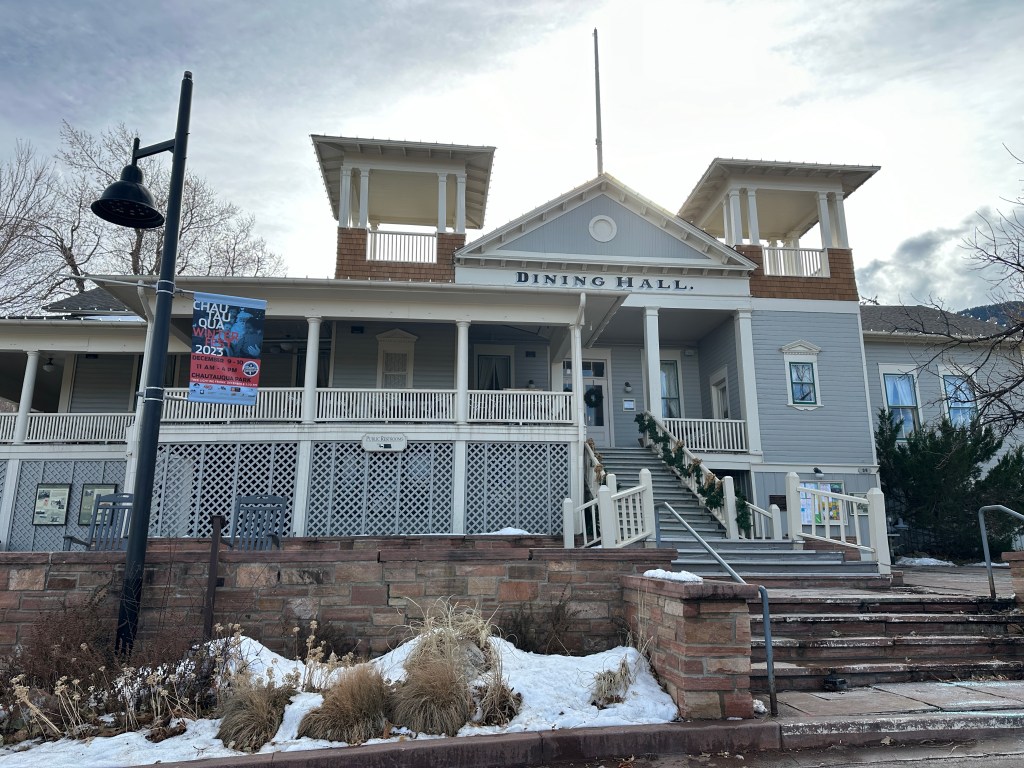 The Chautauqua Dining Hall from the front. It's a blue building with white trimm. There are two stories with a wrap around balcony on the second story.