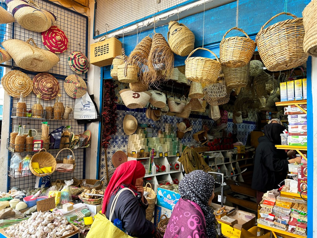 Things to do in Sousse: Visit the medina and walk around, go shopping. You can see the backs of two Muslim women buying spices at a market shop.