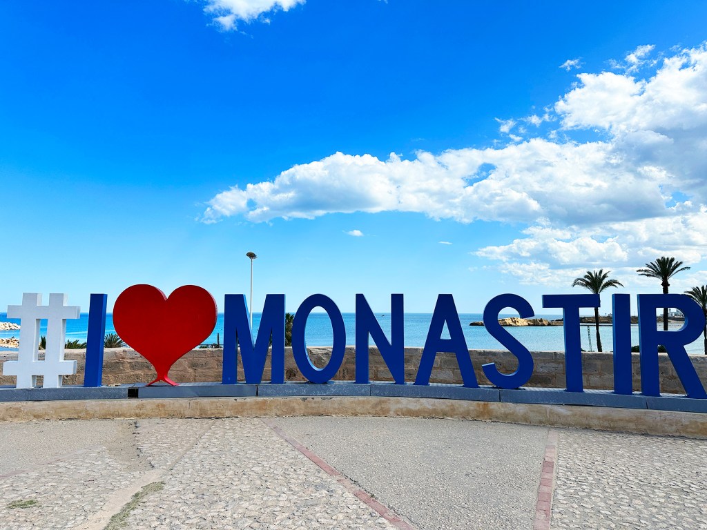 This is the I LOVE MONASTIR sign with the sea behind it.