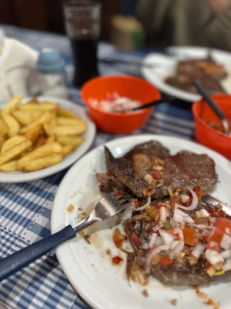 A steak is covered with salsa criolla in Parrilla bar el polo in San Telmo Buenos Aires