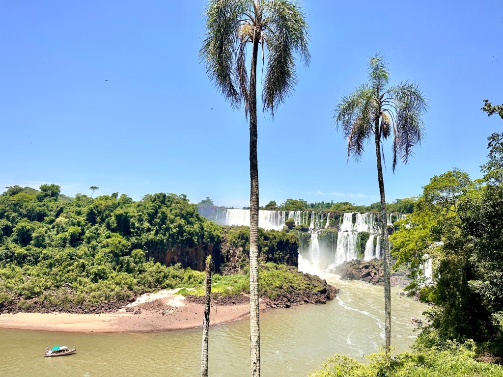 The Iguazu falls from a distance with a boat in front in the water
