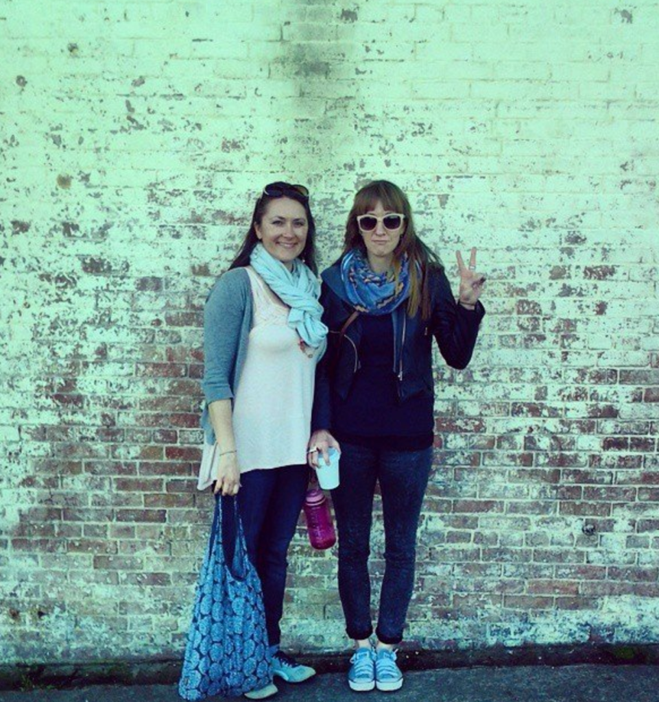 Nicki and Lindsay stand in front of a wall at Alcatraz in san francisco